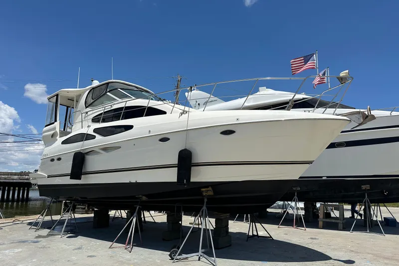 Slide: The Image of 2004 Cruisers Yachts 405 Express Motoryacht on stands, with American flag, under clear blue sky. - 92