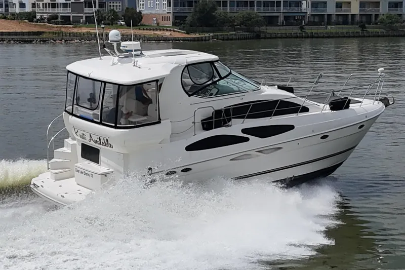 Slide: The Image of 2004 Cruisers Yachts 405 Express Motoryacht cruising on a calm river near waterfront homes. - 2