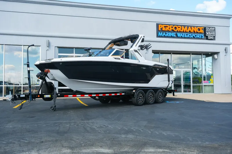 Slide: The Image of 2026 MasterCraft XStar 25 boat on trailer outside Performance Marine Watersports store. - 0