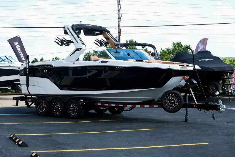 Slide: The Image of 2026 MasterCraft XStar 25 boat on trailer in parking lot, showcasing sleek design. - 1