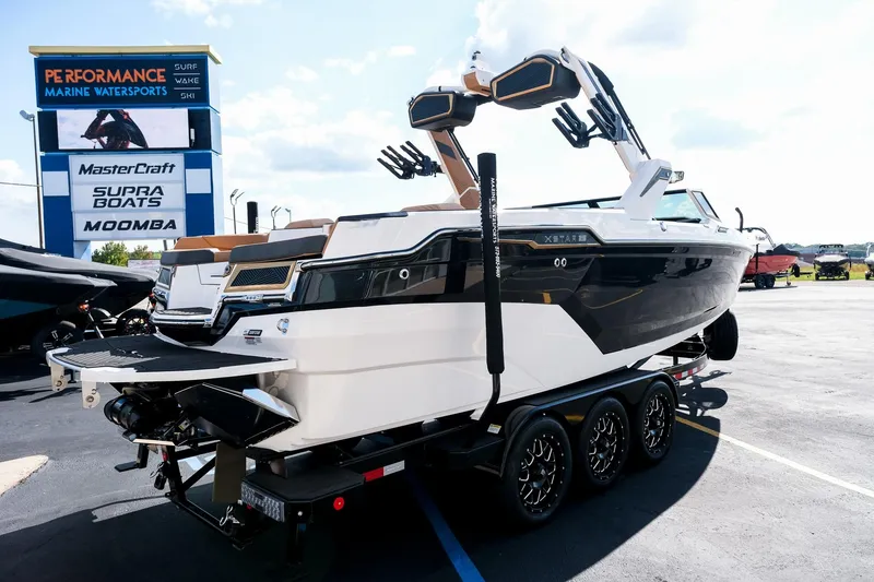 Slide: The Image of 2026 MasterCraft XStar 25 boat on trailer at Performance Marine Watersports dealership. - 11