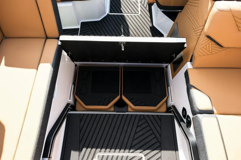 Slide: The Image of 2026 MasterCraft XStar 25 interior storage compartment with tan and black seating. - 36