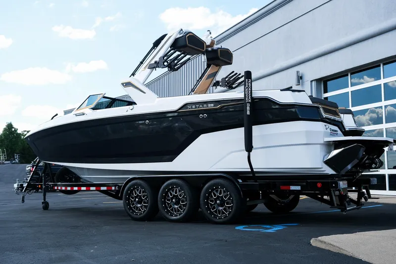 Slide: The Image of 2026 MasterCraft XStar 25 boat on trailer, parked outside a modern building. - 5