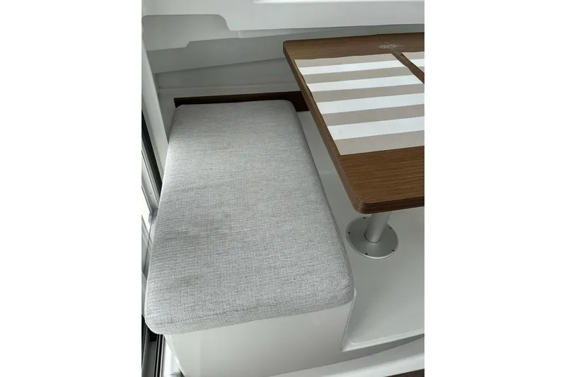 Slide: The Image of 2023 Jeanneau NC Weekender 695 Series 2 interior with cushioned seating and wooden table. - 16