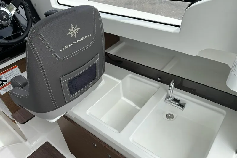 Slide: The Image of 2023 Jeanneau NC Weekender 695 Series 2 interior with steering wheel, seat, and dual sink. - 17