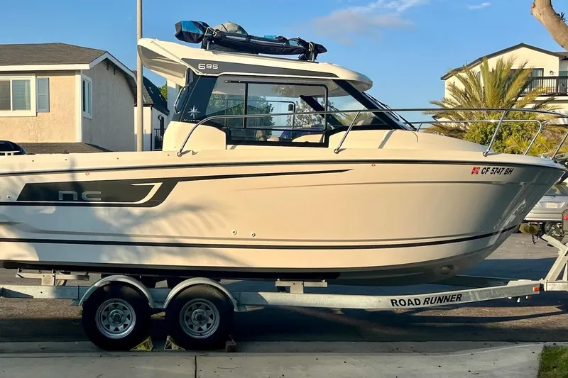 Slide: The Image of 2023 Jeanneau NC Weekender 695 Series 2 boat on trailer, parked in residential area. - 4