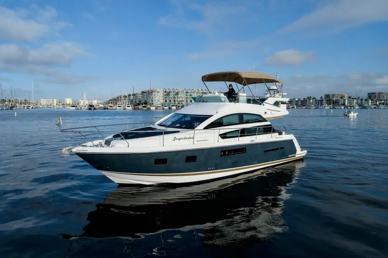 Slide: The Image of 2013 Fairline Squadron 42 yacht cruising in a marina with modern buildings in the background. - 3