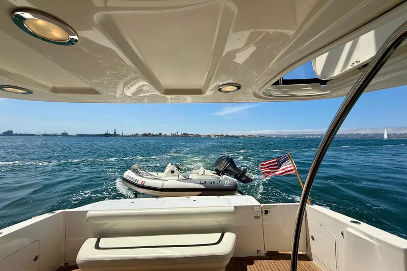 Slide: The Image of 2007 Sea Ray 52 Sedan Bridge yacht with American flag, ocean view, and inflatable boat. - 23