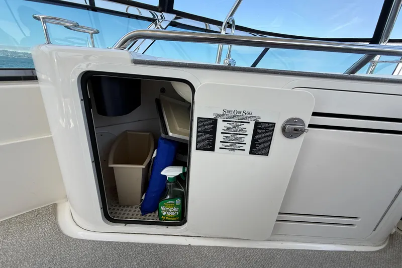 Slide: The Image of 2007 Sea Ray 52 Sedan Bridge storage compartment with cleaning supplies and waste bin. - 30