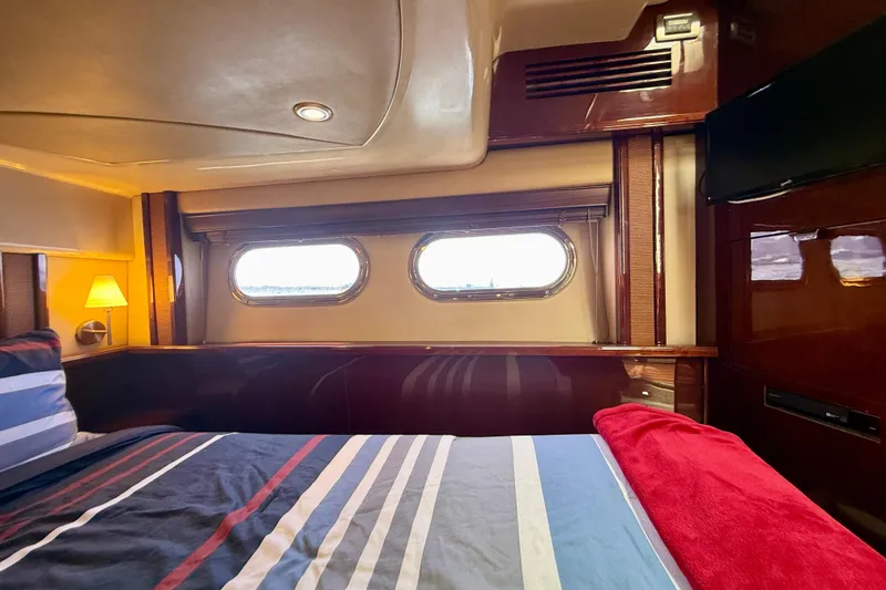 Slide: The Image of Luxurious 2007 Sea Ray 52 Sedan Bridge cabin interior with striped bedding and porthole windows. - 56