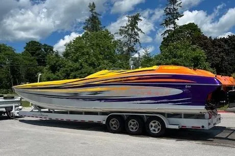 Slide: The Image of 2008 Nor-Tech 3600 Supercat powerboat on trailer, vibrant yellow and purple design, parked outdoors. - 2