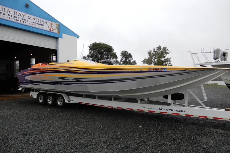 Slide: The Image of 2008 Nor-Tech 3600 Supercat boat on trailer at marina, vibrant yellow and purple design. - 8