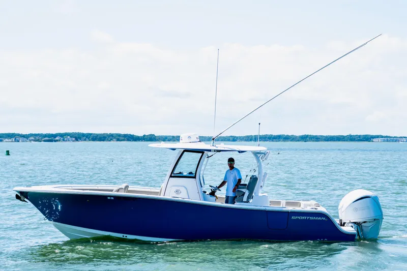 Slide: The Image of 2022 Sportsman Open 282 Center Console boat docked, blue hull, sunny day, waterfront view. - 1