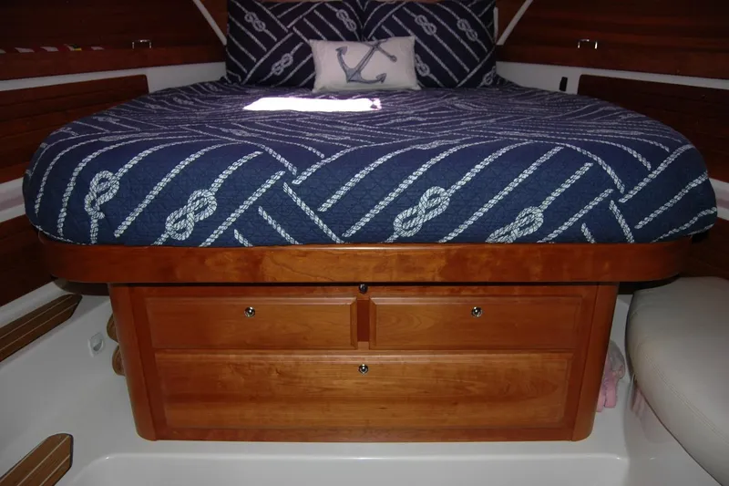 Slide: The Image of 2014 Back Cove 37 cabin interior with nautical bedding and wooden storage drawers. - 102