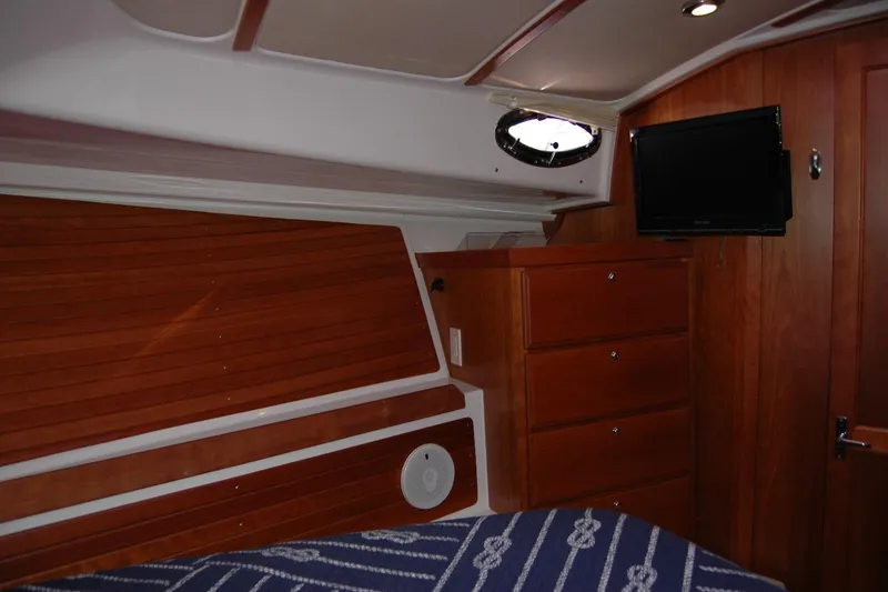 Slide: The Image of 2014 Back Cove 37 interior cabin with wood paneling, drawers, and a mounted TV. - 105