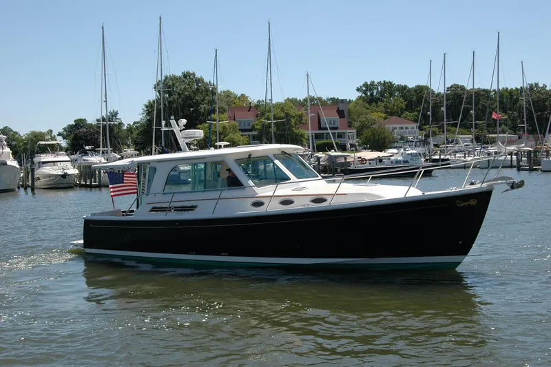 Slide: The Image of 2014 Back Cove 37 boat cruising in a marina with sailboats and waterfront homes. - 11