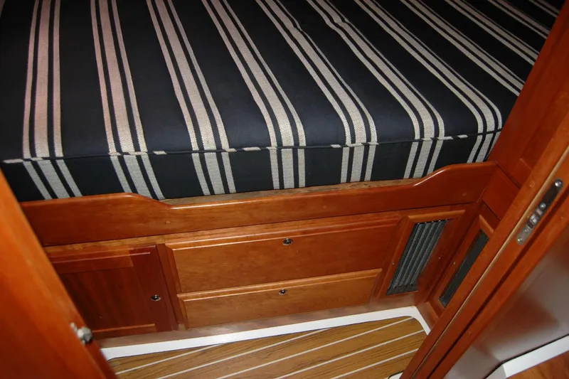 Slide: The Image of 2014 Back Cove 37 interior with striped bedding and wooden cabinetry. - 117