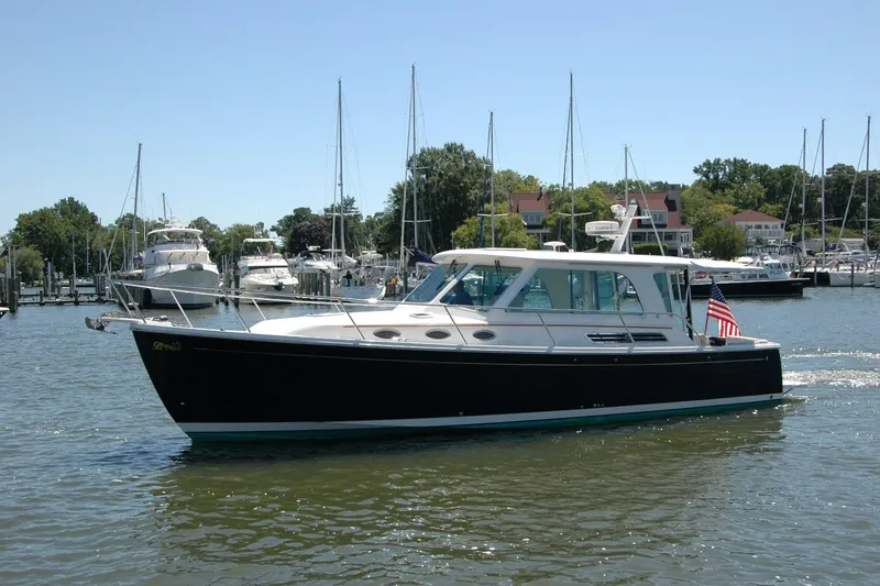 Slide: The Image of 2014 Back Cove 37 yacht cruising in a marina with sailboats and trees in the background. - 13