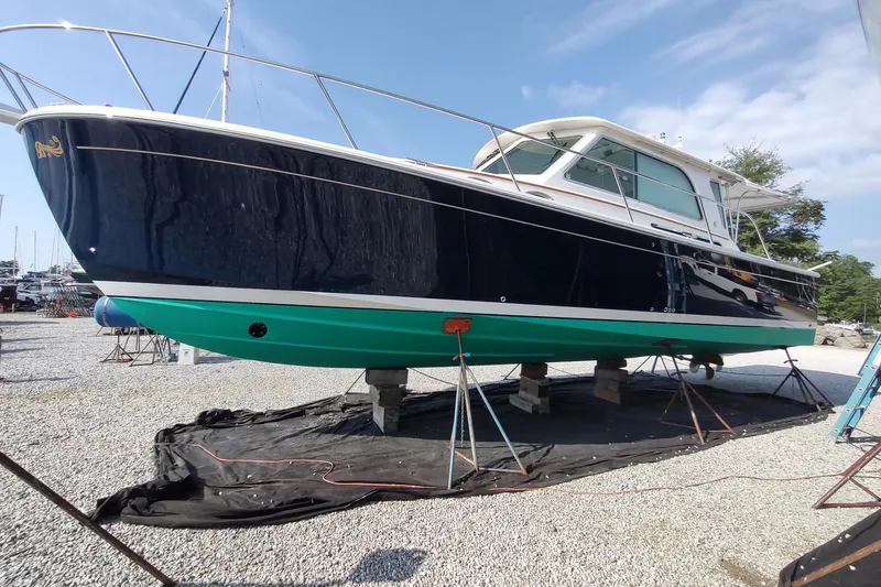 Slide: The Image of 2014 Back Cove 37 boat on stands, blue hull, green bottom, outdoor setting. - 137