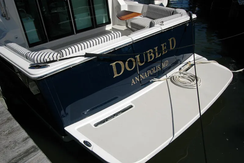 Slide: The Image of 2014 Back Cove 37 boat docked, featuring striped seating and "Double D" name. - 15