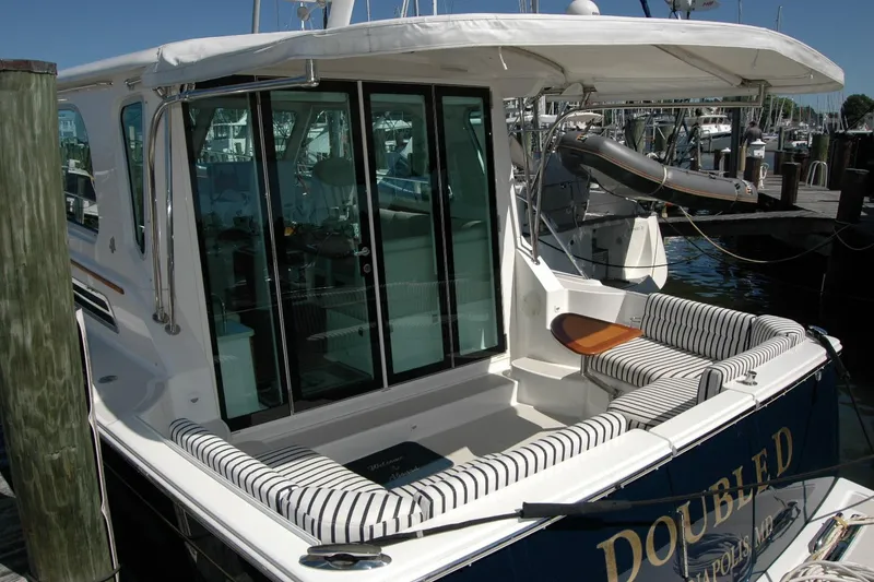 Slide: The Image of 2014 Back Cove 37 yacht with striped seating and glass doors at a marina. - 16