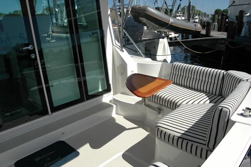 Slide: The Image of 2014 Back Cove 37 yacht with striped seating and wooden table on deck. - 32