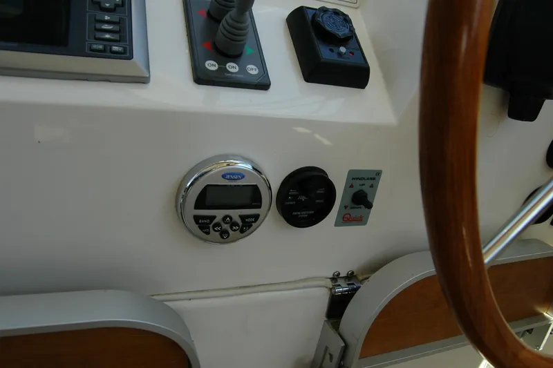 Slide: The Image of Control panel of a 2014 Back Cove 37 boat, featuring various instruments and a wooden steering wheel. - 84