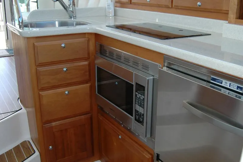 Slide: The Image of 2014 Back Cove 37 yacht kitchen with wooden cabinets, microwave, and stainless steel appliances. - 89