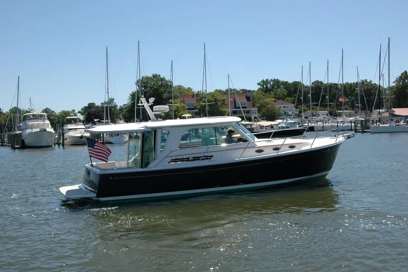 Slide: The Image of 2014 Back Cove 37 boat cruising in a marina with sailboats in the background. - 9