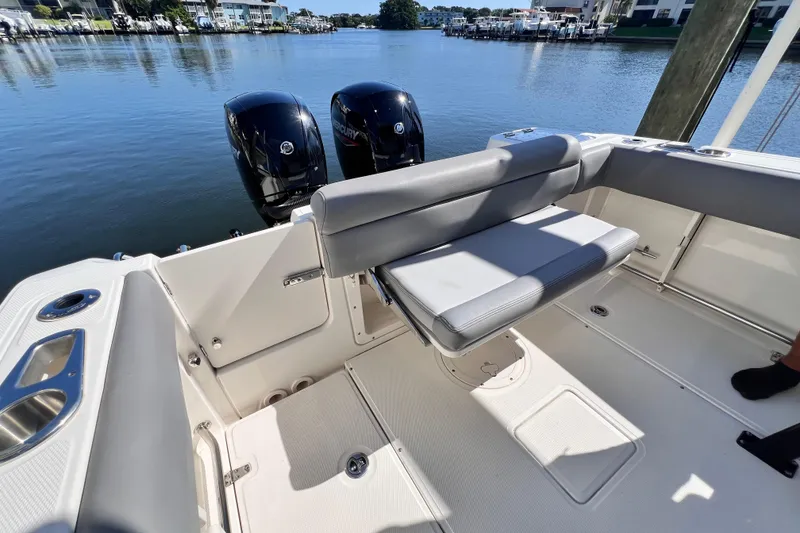 Slide: The Image of 2023 Boston Whaler 230 Outrage boat interior with dual Mercury engines, docked by waterfront. - 12