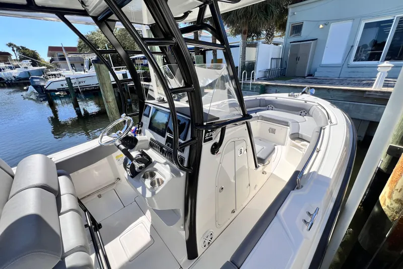 Slide: The Image of 2023 Boston Whaler 230 Outrage boat interior with helm and seating, docked by the water. - 15