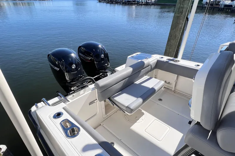 Slide: The Image of 2023 Boston Whaler 230 Outrage boat with dual Mercury engines docked by the water. - 16