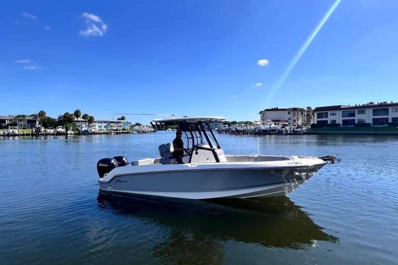 Slide: The Image of 2023 Boston Whaler 230 Outrage boat on calm water under clear blue sky. - 3