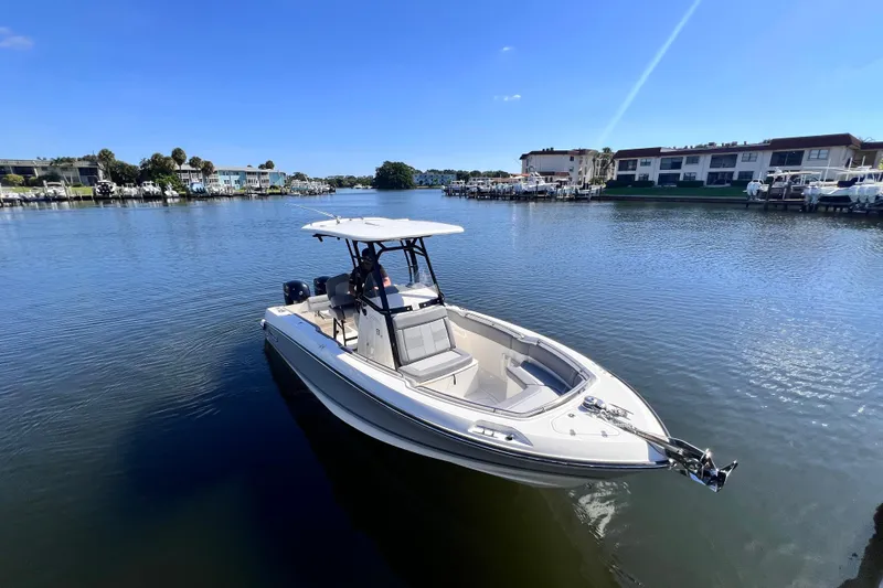 Slide: The Image of 2023 Boston Whaler 230 Outrage boat on calm water, sunny day, residential backdrop. - 6