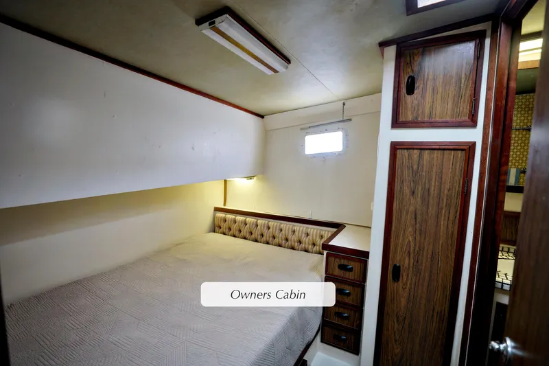 Slide: The Image of Owner's cabin in 1980 Pacifica 41 Sportfisher, featuring cozy bed and wooden cabinetry. - 13