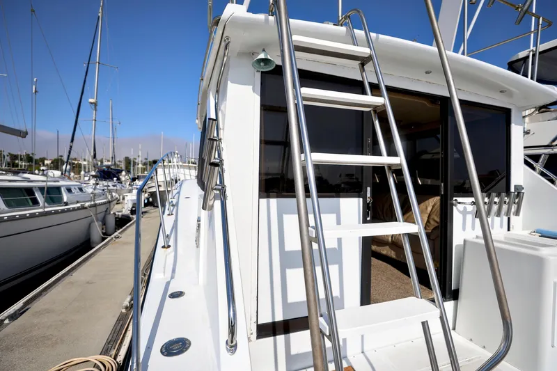 Slide: The Image of 1980 Pacifica 41 Sportfisher yacht docked at marina with ladder and open cabin door. - 2