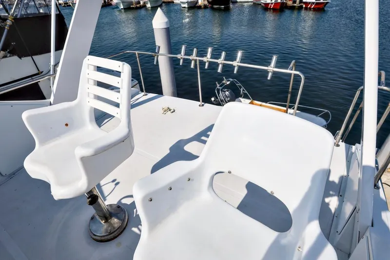 Slide: The Image of 1980 Pacifica 41 Sportfisher boat deck with white chairs and fishing rod holders. - 5