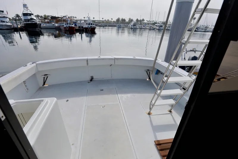 Slide: The Image of 1980 Pacifica 41 Sportfisher boat deck with marina view, featuring ladder and spacious layout. - 7