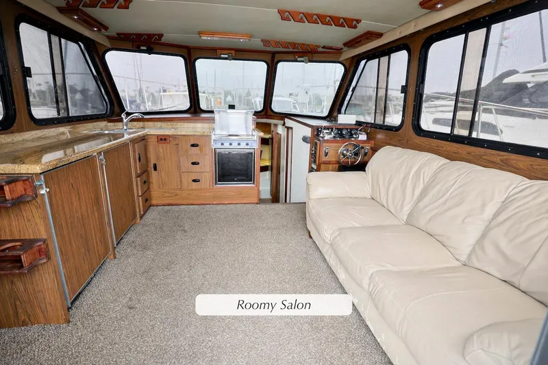 Slide: The Image of Roomy salon interior of 1980 Pacifica 41 Sportfisher with beige sofa and wooden cabinetry. - 8