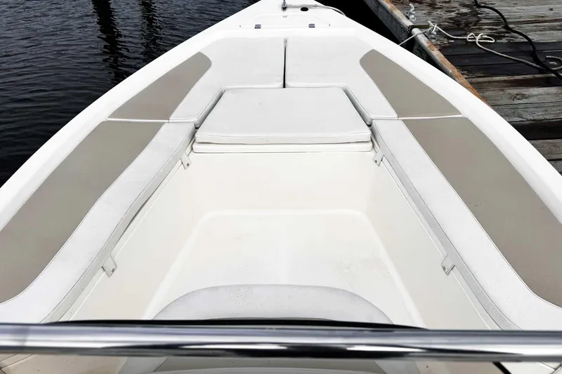 Slide: The Image of 2021 Bulls Bay 2200 boat interior with cushioned seating, docked by wooden pier. - 12