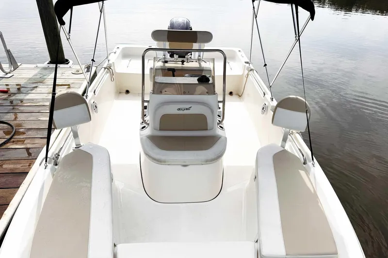 Slide: The Image of 2021 Bulls Bay 2200 boat interior with seating and console, docked by calm water. - 13