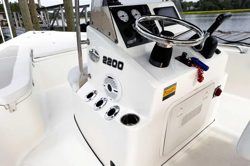 Slide: The Image of 2021 Bulls Bay 2200 boat console with steering wheel and controls, docked by the water. - 16