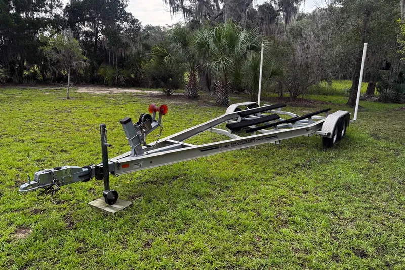Slide: The Image of 2021 Bulls Bay 2200 boat trailer on grassy field with trees in background. - 26