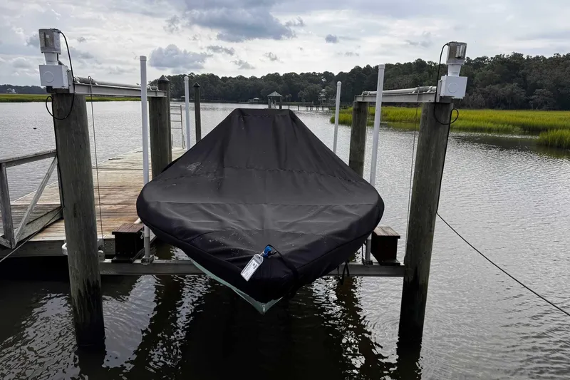 Slide: The Image of 2021 Bulls Bay 2200 boat covered at dock, surrounded by calm water and greenery. - 28