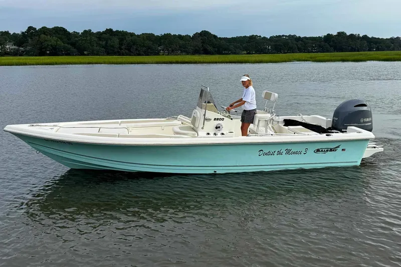 Slide: The Image of 2021 Bulls Bay 2200 boat on water, person steering, Yamaha engine visible. - 4