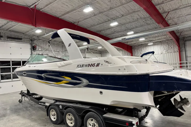 Slide: The Image of 2005 Four Winns 290 Horizon boat in a garage, on a trailer, with sleek design. - 3