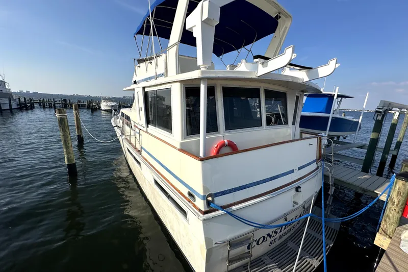 Slide: The Image of 1985 Chris-Craft 500 Constellation yacht docked at marina, featuring classic design and blue canopy. - 136