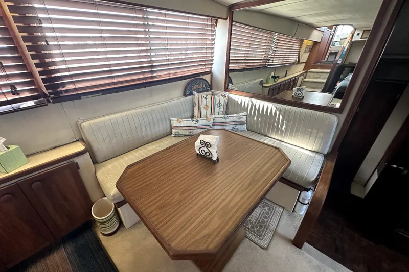 Slide: The Image of 1985 Chris-Craft 500 Constellation interior with wood table, cushioned seating, and blinds. - 23