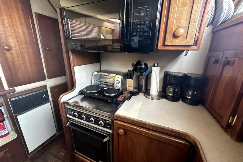 Slide: The Image of 1985 Chris-Craft 500 Constellation yacht kitchen with stove, microwave, and wooden cabinets. - 36