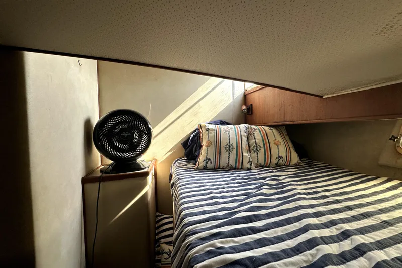 Slide: The Image of Cozy cabin interior of 1985 Chris-Craft 500 Constellation with striped bedding and a fan. - 44